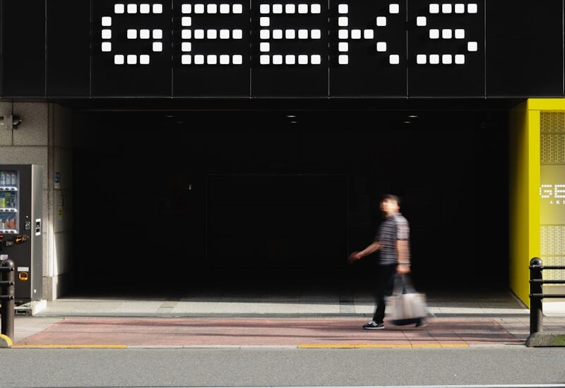 A man walking down a street next to a tall building