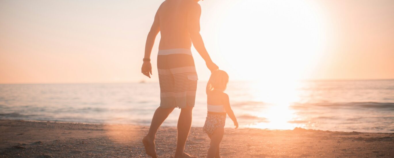 man holding girl heading towards sea