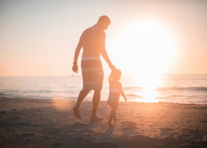 man holding girl heading towards sea