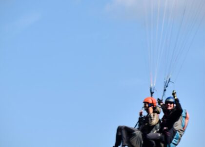 man in black jacket and orange helmet riding on red and black parachute